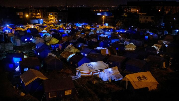 Victimes du séisme du 6 février, des résidents d'Hatay, au sud de la Turquie, suivent les résultats du premier tour des élections sous des tentes, le 14 mai 2023. (CAN EROK / AFP)