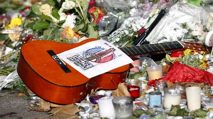 &nbsp; (Une guitare posée parmi les bouquets de fleurs en hommage aux victimes devant le Bataclan © REUTERS/Charles Platiau)