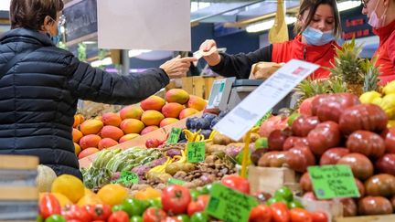 Une cliente paie ses achats, sur un marché de Nancy, le 13 novembre 2021. (NICOLAS GUYONNET / HANS LUCAS / AFP)