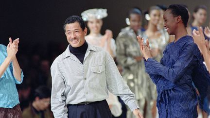 Issey Miyake, sourire radieux, applaudi par ses mannequins et des personnes ayant assisté à son défilé, le 19 octobre 1991 à Paris, quand il présentait sa collection printemps-été 1992... (PIERRE GUILLAUD / AFP)