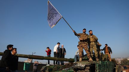 Des rebelles agitent un drapeau islamique sur un char, le 9 décembre 2024 à Damas (Syrie). (OMAR HAJ KADOUR / AFP)