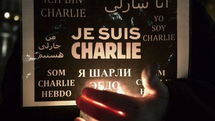 A woman holds a candle and a poster reading "I am Charlie" during a gathering in Strasbourg, eastern France, on January 8, 2015 (FREDERICK FLORIN / AFP)