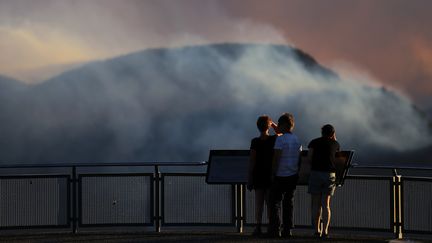 Des gens observent la fumée de l'incendie de Green Wattle Creek en Nouvelle-Galles du Sud, le 6 décembre 2019. (STRINGER / REUTERS)