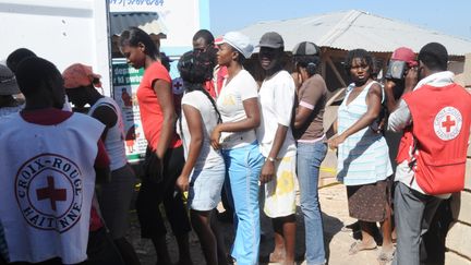 Des employ&eacute;s de la Croix-Rouge distribuent des kits de pr&eacute;vention contre le cholera, dans la banlieue de Port-au-Prince, en Ha&iuml;ti,&nbsp;le 11 f&eacute;vrier 2011. (THONY BELIZAIRE / AFP)