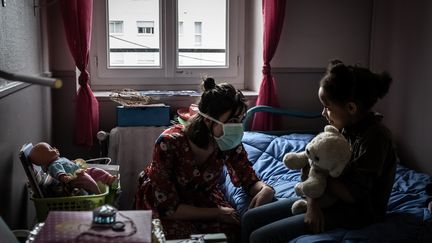 Une éducatrice portant un masque discute avec une petite fille dans un centre social près de Lyon. (JEAN-PHILIPPE KSIAZEK / AFP)