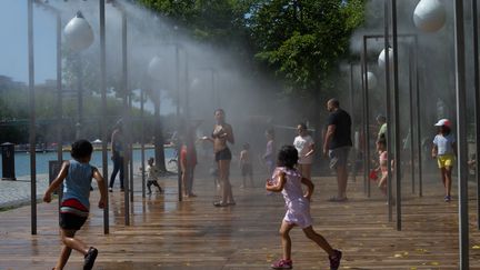 Enfants et adultes cherchent à se rafraîchir à Paris, le 9 août 2020. (PATRICIA MORIBE / HANS LUCAS / AFP)