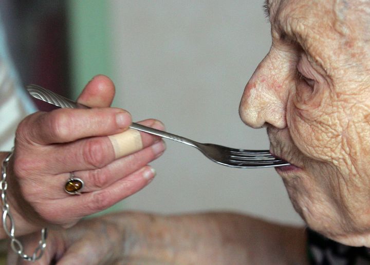 Une personne donne à manger à une dame agée. (ROMAIN PERROCHEAU / AFP)