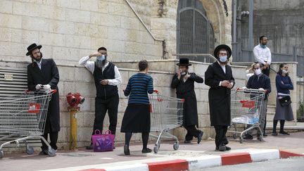 Des Juifs ultra-orthodoxes portent des masques alors qu'ils font la queue&nbsp;devant une enseigne, à&nbsp;Bnei Brak, en Israël, le 6 avril 2020. (MENAHEM KAHANA / AFP)