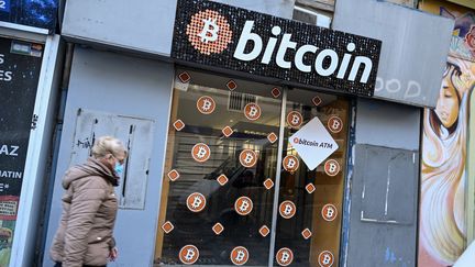 Une femme passe devant la vitrine d'un magasin spécialisé dans le bitcoin, à Marseille, le 8 janvier 2021. (NICOLAS TUCAT / AFP)