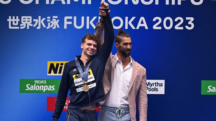 La légende américaine, Michael Phelps, célèbre son héritier Léon Marchand, nouveau recordman du monde du 400 m quatre nages, le 23 juillet 2023 à Fukuoka (Japon). (MANAN VATSYAYANA / AFP)