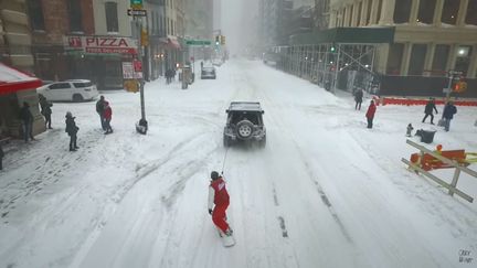 Un New-Yorkais en snowboard se fait tracter par un 4x4, à New York, pendant la tempête Jonas, le 23 janvier 2016. Au moins 19 personnes sont mortes dans ce qui contistitue une des pires tempêtes de neige de l'histoire de la côte Est des Etats-Unis. (CASEY NEISTAT / YOUTUBE)