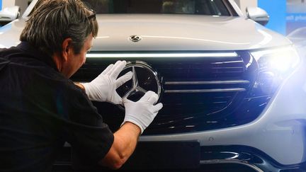 Un salarié de l'usine Mercedes-Benz de Brême (Allemagne) fixe le logo sur la calandre d'un véhicule le 29 janvier 2020. (PATRIK STOLLARZ / AFP)