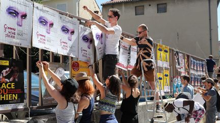 Les colleurs d'affiche du festival "off" se ruent sur le moindre petit espace libre pour présenter les spectacles, le 5 juillet 2017 à Avignon (Vaucluse). (PATRICK ROUX / MAXPPP)