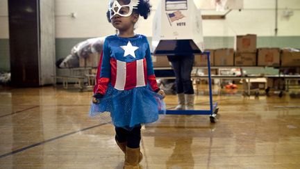 Une enfant porte un d&eacute;guisement du personnage de bande dessin&eacute;e "Captain America" dans un bureau de vote de Staten Island (New&nbsp;York), mardi 6 novembre 2012. (ALLISON JOYCE / GETTY IMAGES / AFP)