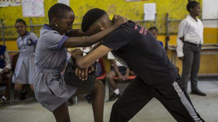 Bouclier de cuir en main, l'instructrice donne ses consignes. Ses élèves du jour, des écolières de 11 ans, s'exécutent sans broncher et rouent la cible de violents coups de genou. Face aux élèves de l'école Thabisang, une des formatrices de l'ONG ABS, Dimakatso Monokoli, donne ses conseils. «Ne commettez jamais l'erreur de vous retrouver seules dans la même pièce que quelqu'un qui vous rend mal à l'aise. Faites confiance à votre instinct», leur lance-t-elle. Et en cas d'agression, «criez autant que vous pouvez». «On ne va pas vous apprendre à donner des coups de poing, mais à vous battre de façon intelligente, sans force», renchérit un de ses collègues masculins. Suivent des démonstrations de coups portés aux tibias, à la veine jugulaire, aux parties génitales. «Vous pouvez aussi arracher les oreilles, les narines», détaille l'instructeur. Les filles passent à l'action. Dans leur uniforme – robe bleu et soquettes blanches –, elles se déchaînent. Quelques rires, mais l'ambiance reste studieuse. Conquis par l'approche d'ABS, qui a sensibilisé plus de 13.000 enfants dans le pays, le ministère sud-africain de la Santé vient de faire appel à l'ONG pour former 160 instructeurs antiviol. (GULSHAN KHAN / AFP)