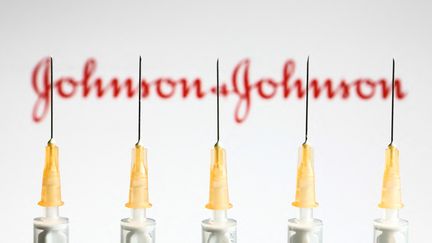 Des seringues devant le logo du laboratoire Johnson &amp; Johnson, à Cracovie, en Pologne, le 14 avril 2021. (JAKUB PORZYCKI / NURPHOTO / AFP)