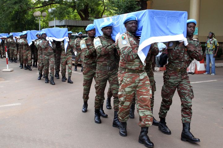 Des soldats nigériens de la Minusma portent les cercueils&nbsp;aux couleurs de l'ONU&nbsp;de neufs soldats à Bamako, le 7 octobre 2014. (HABIBOU KOUYATE / AFP)