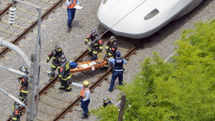 Un bless&eacute; est &eacute;vacu&eacute; d'un train Shinkansen, apr&egrave;s l'immolation d'un passager, le 30 juin 2015, &agrave; Odawara (Japon). (KYODO KYODO / REUTERS)