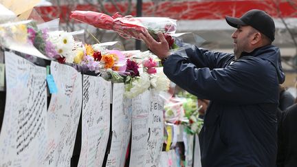 Un homme dépose des fleurs, le 24 avril 2018, sur un mémorial rendant hommage aux victimes de l'attaque à la voiture bélier de Toronto (Canada), qui a fait 10 morts la veille. (LARS HAGBERG / AFP)