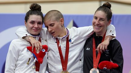 La Française Marie Patouillet, victime d'un malaise, soutenue par sa compatriote Heïdi Gaugain et la Néo-Zélandaise Nicole Murray sur le podium de la poursuite individuelle 3 000 m en cyclisme sur piste aux Jeux paralympiques 2024, à Saint-Quentin-en-Yvelines, le 1er septembre 2024. (ELSA / GETTY IMAGES EUROPE)