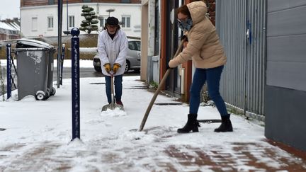 Residents of Armentières (North) clean a snowy sidewalk, December 3, 2023. (FLORENT MOREAU / MAXPPP)