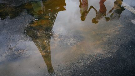 Des touristes sous la pluie près de la Tour Eiffel à Paris, le 17 août 2024. (DIMITAR DILKOFF / AFP)