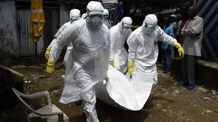 Des salariés de la Croix-Rouge portent le corps d'une personne possible morte du virus Ebola, le 4 octobre 2014 à Monrovia (Liberia).&nbsp; (PASCAL GUYOT / AFP)