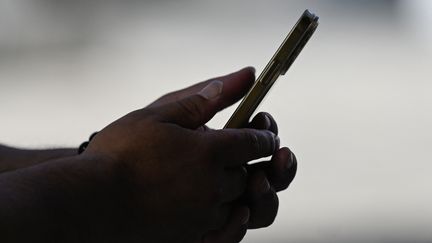 Un homme regarde l'écran de son smartphone. (PEDRO PARDO / AFP)