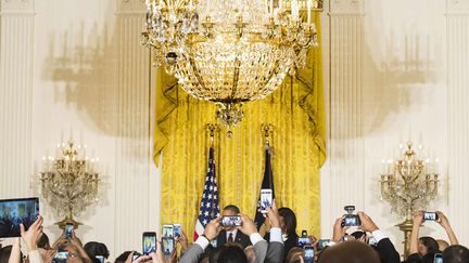 Les invit&eacute;s du pr&eacute;sident am&eacute;ricain Barack Obama et de son &eacute;pouse brandissent des t&eacute;l&eacute;phones portables pour les photographier lors d'un discours c&eacute;l&eacute;brant le mois de l'histoire des Noirs &agrave; la Maison Blanche &agrave; Washington (Etats-Unis), le 26 f&eacute;vrier 2015. (JIM WATSON / AFP)