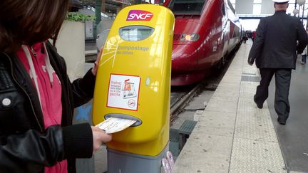 Une femme composte son billet avant de prendre le train, le 3 mai 2013 en gare de Lille (Nord). (DENIS CHARLET / AFP)