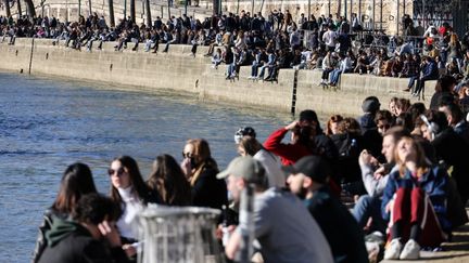 Des Parisiens prennent un bain de soleil le 27 février 2021 sur les quais de Seine. (THOMAS COEX / AFP)