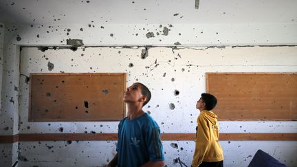 De jeunes palestiniens inspectent une salle de classe endommagée par une frappe aérienne israélienne, à Al-Maghazi dans le centre de la bande de Gaza, le 18 octobre 2023. (MAJDI FATHI / NURPHOTO via AFP)