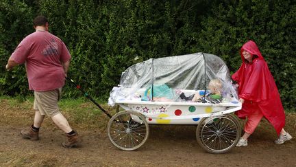 Des festivaliers et leurs enfants affrontent Glastonbury&nbsp;(Royaume-Uni) sous la pluie, le 26 juin 2014. (CATHAL MCNAUGHTON / REUTERS)