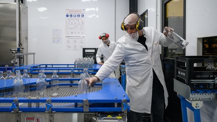 Un ouvrier manipule des bouteilles à traiter à l'usine Be WTR à Paris, le 11 septembre 2024. (ED JONES / AFP)