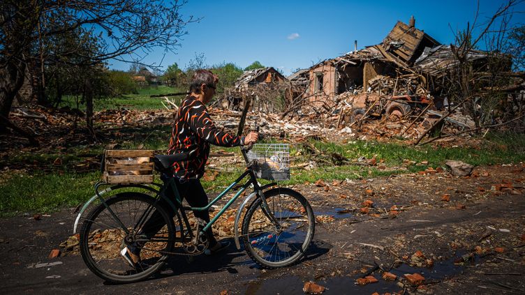 Une habitante de Siversk, dans la région ukrainienne de Donetsk, passe devant une maison détruite, le 2 mai 2023. (DIMITAR DILKOFF / AFP)