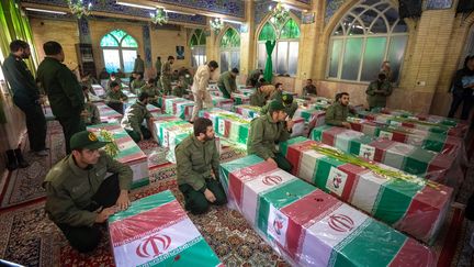 Des militaires iraniens se recueillent lors des funérailles de victimes de l'attentat revendiqué par l'Etat islamique, le 5 janvier 2024 à Kerman (Iran). (AMIR MORADI / MIDDLE EAST IMAGES / AFP)