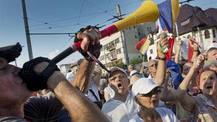 ​Manifestation devant le Palais de Cotroceni, le siège et la présidence roumaine à Bucarest, le 10 août 2014. Des manifestants crient des slogans contre le président conservateur Traian Basescu qu'ils appellent à la démission. Ils l'accusent d'être à l'origine de la condamnation à 10 ans de prison de Dan Voiculescu, patron d'une station de télévision commerciale, pour blanchiment d'argent. (AFP PHOTO / DANIEL MIHAILESCU)