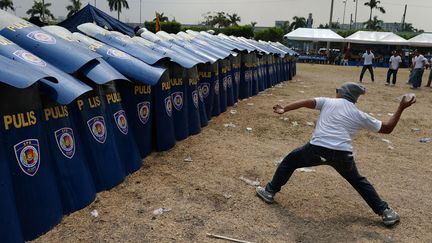 Un faux manifestant lance une bombe &agrave; eau sur des policiers lors d'un entra&icirc;nement &agrave; Manille (Philippines) avant la venue du pr&eacute;sident am&eacute;ricain, Barack Obama, le 23 avril 2014. (NOEL CELIS / AFP)