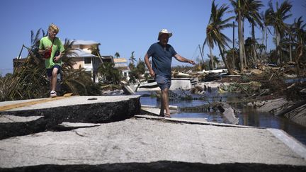 Des résidents de l'île de Pine Island (Floride), marchent dans les décombres après le passage de l'ouragan Ian. Les vents forts et les pluies ont causé de graves dégâts.&nbsp;&nbsp; (WIN MCNAMEE / GETTY IMAGES NORTH AMERICA / AFP)