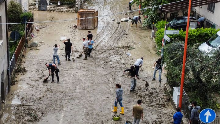 Des habitants de Cesena nettoient la boue après les fortes pluies dans le nord de l'Italie, le 18 mai 2023. (ALESSANDRO SERRANO / AFP)