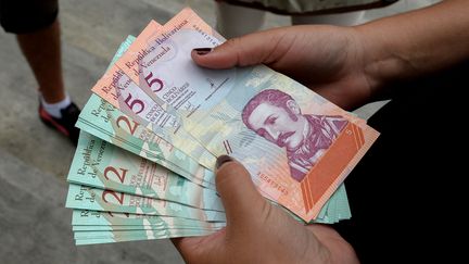 Une femme tient des billets de bolivars souverains, le 21 août 2018, à Caracas au Venezuela. (FEDERICO PARRA / AFP)