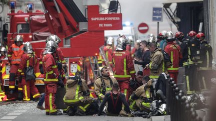 Les pompiers, exténués, après leur intervention&nbsp;pour éteindre l'incendie, rue de Trévise, à Paris. (GEOFFROY VAN DER HASSELT / AFP)