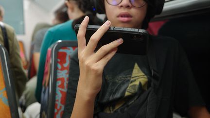 Un adolescent joue à un jeu vidéo sur son téléphone dans le métro à Paris, le 16 septembre 2023. (MYRIAM TIRLER / HANS LUCAS / AFP)