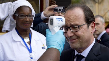 Le pr&eacute;sident fran&ccedil;ais Fran&ccedil;ois Hollande se fait prendre la temp&eacute;rature &agrave; son arriv&eacute;e &agrave; l'h&ocirc;pital Donka &agrave; Conakry (Guin&eacute;e), le 28 novembre 2014. (ALAIN JOCARD / AFP)