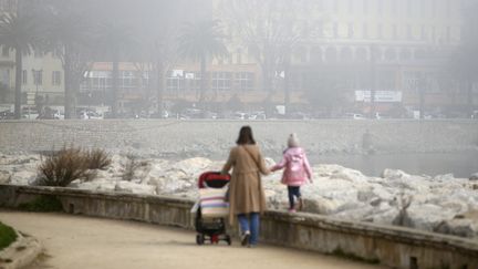 Une femme et ses enfants marchent dans une rue d'Ajaccio alors qu'un nuage de pollution enveloppe la ville, le 25 février 2021. (PASCAL POCHARD-CASABIANCA / AFP)