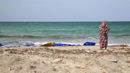 Une femme devant des débris et des gilets de sauvetage rejetés par la mer Méditerranée, le 21 septembre 2017, sur une plage de&nbsp;Zouara, en Libye. (Photo d'illustration) (AFP)