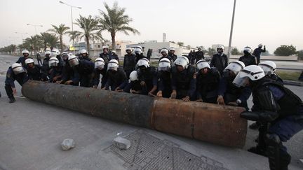 Des policiers d&eacute;placent un tuyau install&eacute; sur une route par les manifestants anti gouvernementaux &agrave; Budaiya (Bahra&iuml;n), le 17 d&eacute;cembre 2011. (HAMAD I MOHAMMED / REUTERS)