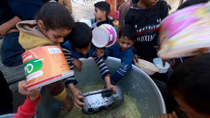 Des enfants récupèrent de la nourriture lors d'une distribution humanitaire à Rafah, dans la bande de Gaza, le 6 décembre 2023. (MOHAMMED ABED / AFP)