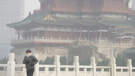 Un homme marche à Nanchang (Chine) sous un épais nuage de pollution, le 5 décembre 2017. (MAXPPP)