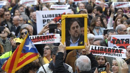 Des manifestants catalans défilent, le 2 mai 2018 à Barcelone, avec le portrait d'Oriol Junqueras, l'un des dirigeants renvoyés devant la justice. (LLUIS GENE / AFP)